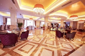 A spacious lobby with a geometric patterned floor, a reception desk, and seating areas. - Jasmine International Hotel (Renshou)