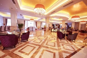 A spacious lobby with a geometric patterned floor, a reception desk, and seating areas.