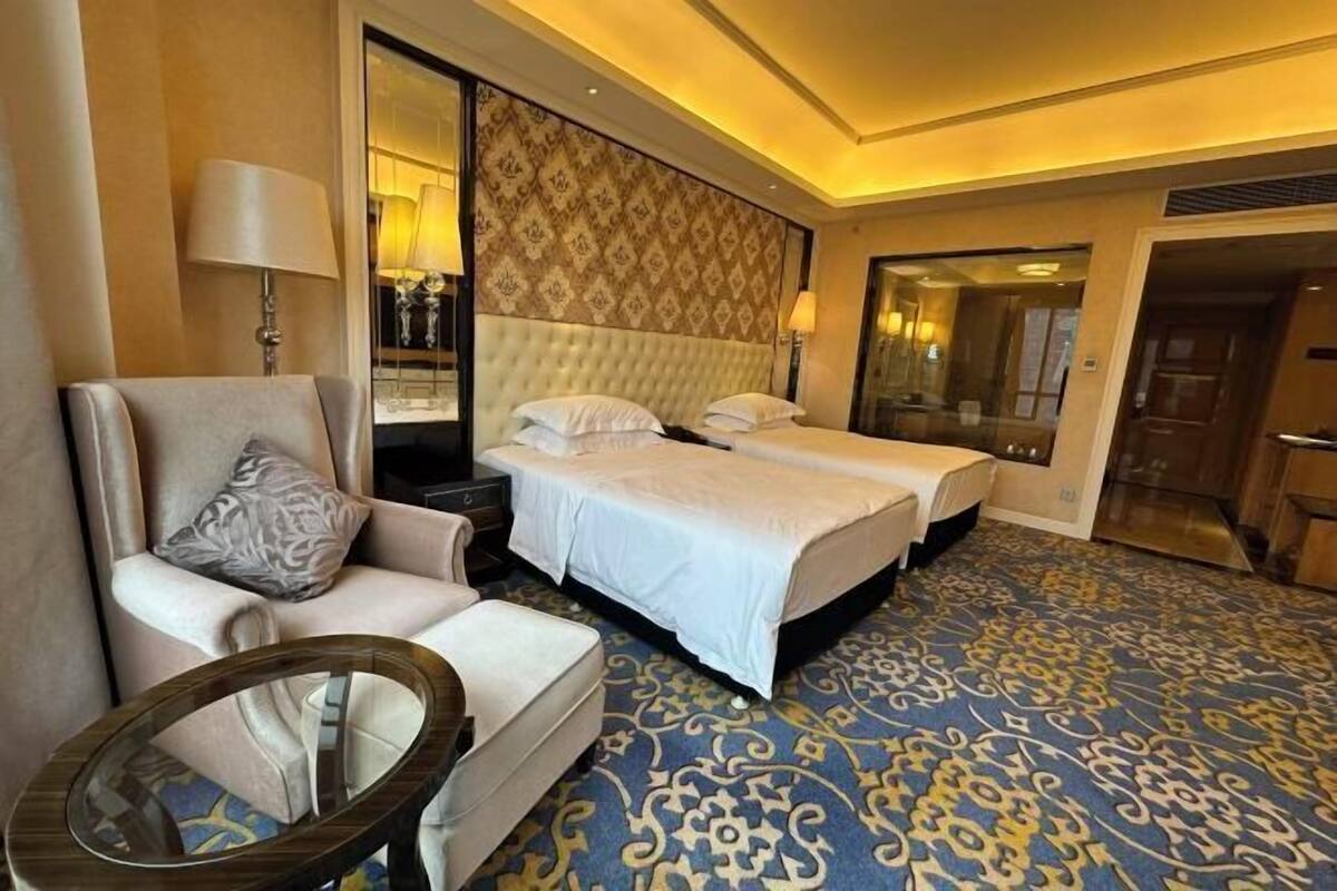A hotel room with a large bed, a sofa, a round table, and a patterned carpet.