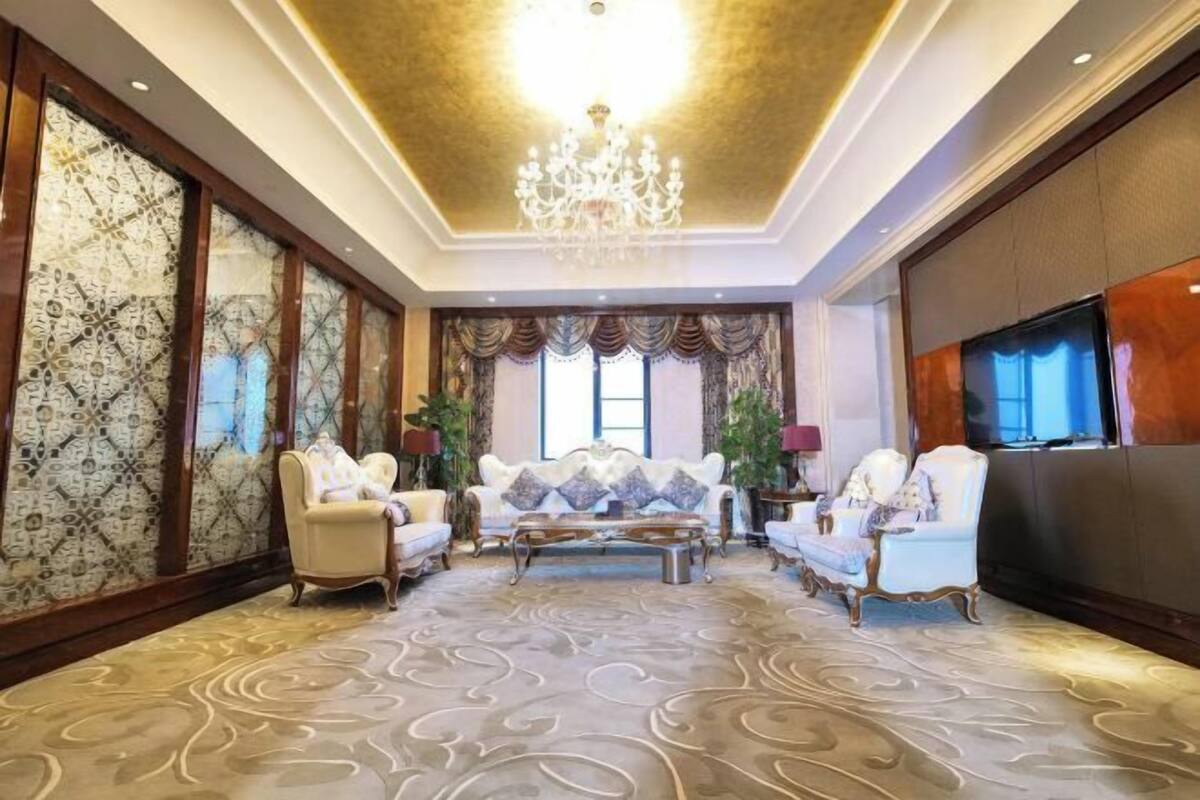 A spacious living room with a chandelier, plush sofas, and a large flat-screen TV.