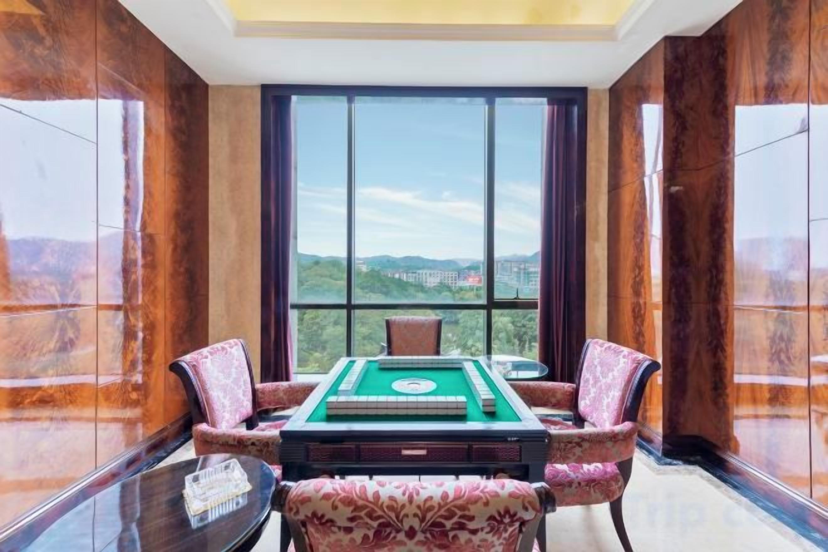 Habitación con mesa de billar, dos sillas y un ventanal con vistas.