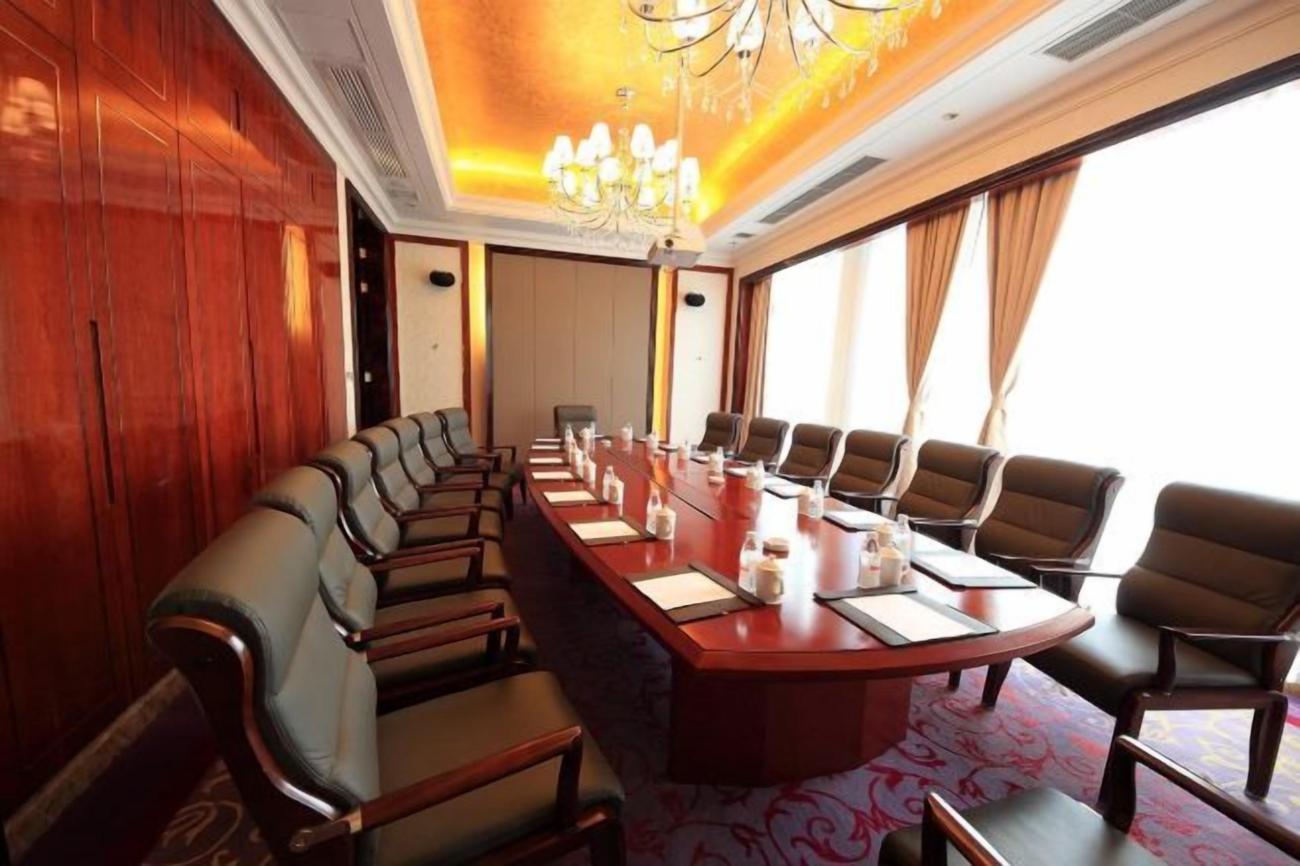 A conference room with a long table, multiple chairs, and a chandelier.