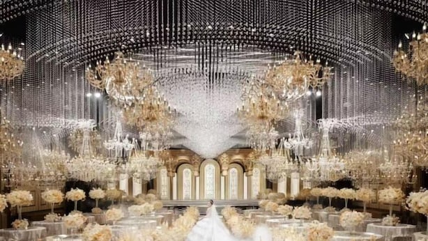 A grand hall with a central aisle leading to an ornate altar, surrounded by circular tables with floral arrangements. - Jasmine International Hotel (Renshou)