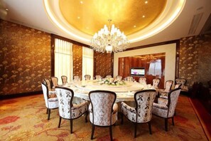 A conference room with a round table, chairs, a chandelier, and a television screen. - Jasmine International Hotel (Renshou)
