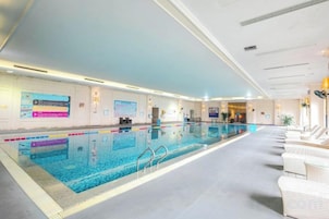 Piscina interna com pistas demarcadas, cadeira de salva-vidas e área de recepção com balcão.