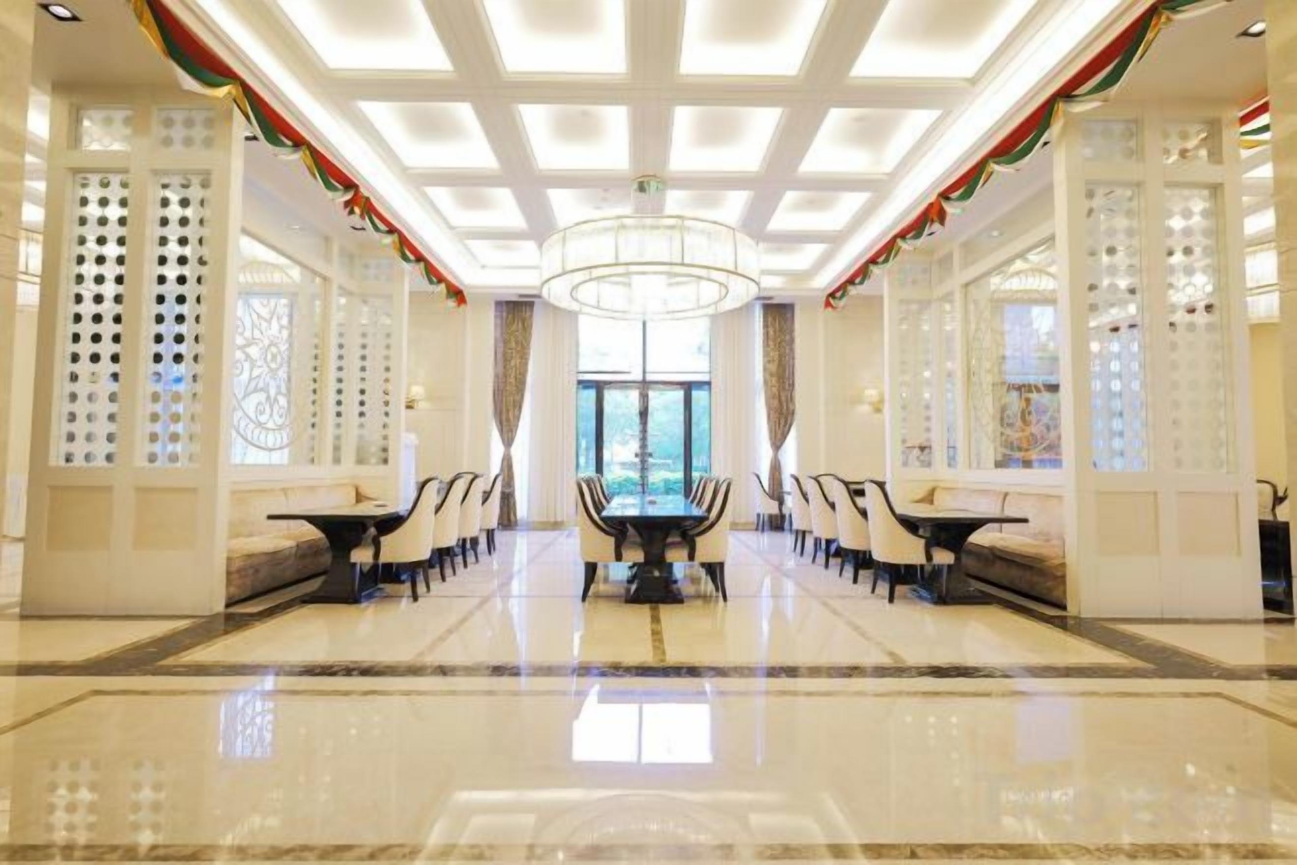 A spacious lobby with a central seating area, a chandelier, and decorative elements.