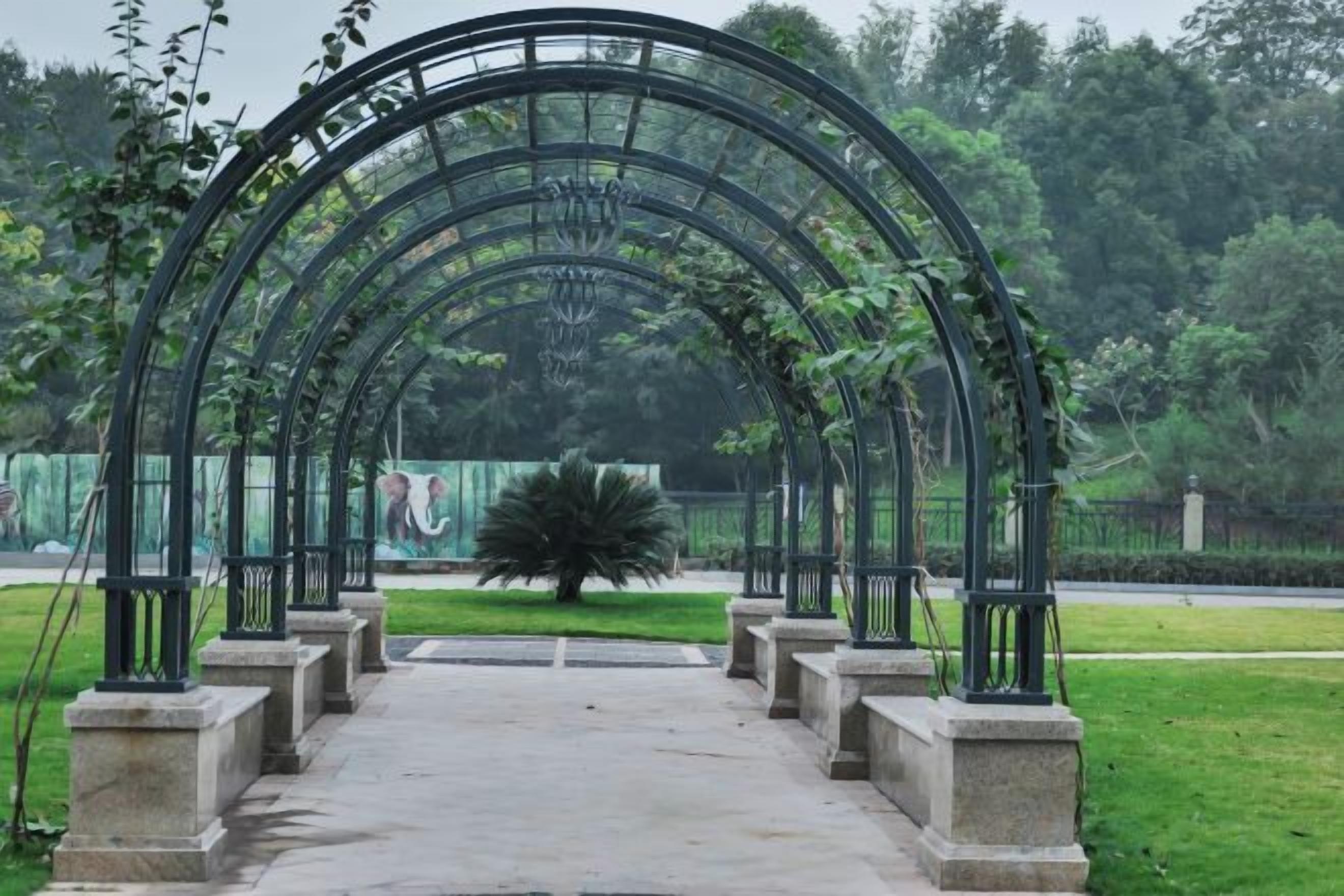 A stone pathway leading to a metal archway in a park.