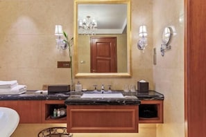 A bathroom with a marble sink, a large mirror, wall sconces, and a wooden door. - Jasmine International Hotel (Renshou)