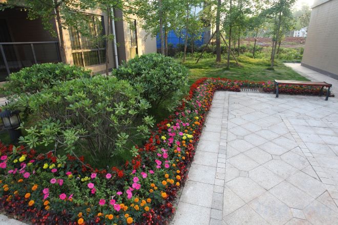 A landscaped outdoor area with a paved walkway, benches, and flower beds.