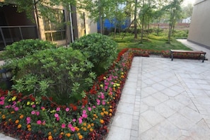 A landscaped outdoor area with a paved walkway, benches, and flower beds. - Jasmine International Hotel (Renshou)