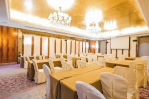 A conference room with tables and chairs, a projector screen, and a chandelier. - Jasmine International Hotel (Renshou)