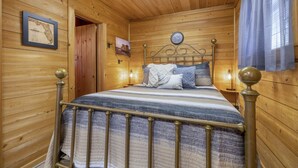 Une chambre à coucher dans une cabane en bois, avec un lit, une horloge murale et une carte encadrée.