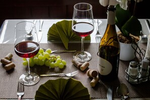 A table set with wine glasses, a bottle of wine, grapes, and a potted plant. - Hotel Villa Huber (Afritz am See)