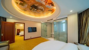 A hotel room with a large bed, a television, a glass shower enclosure, and a ceiling with a decorative design. - Vienna Hotel (Jishou Railway Station) (Jishou)