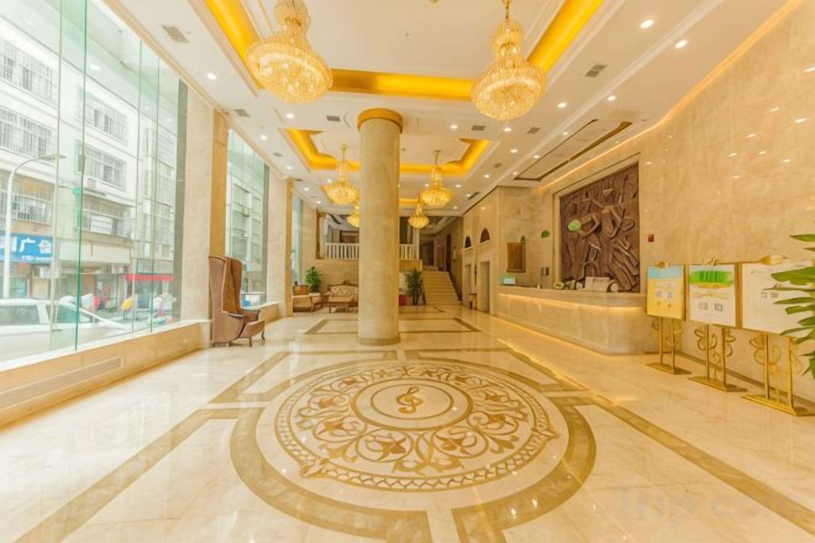 Vestíbulo de hotel con mostrador de recepción, ventanas amplias y un diseño decorativo en el piso.