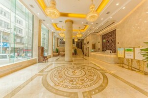 Vestíbulo de hotel con mostrador de recepción, ventanas amplias y un diseño decorativo en el piso.
