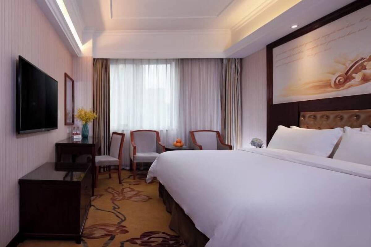 Une chambre d’hôtel avec un lit, une télévision, un bureau et une chaise.