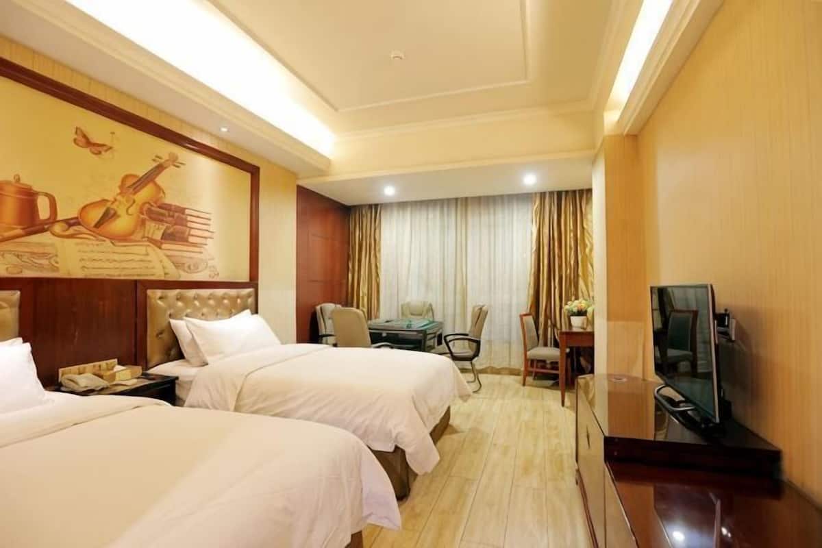 Une chambre d’hôtel avec deux lits, une télévision, un bureau et une chaise.