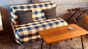 A checkered sofa with dark cushions, a wooden table, and a stone-tiled floor.