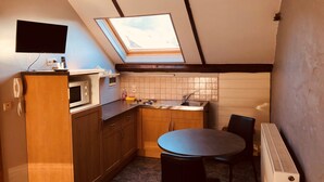 A compact kitchen with a skylight, a microwave, a stove, and a small dining area with two chairs.