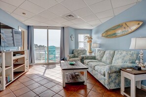 Un salon avec un canapé, une table basse et une planche de surf accrochée au mur.