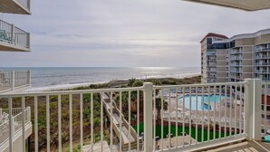 Uma varanda com vista para a praia e para a área da piscina.