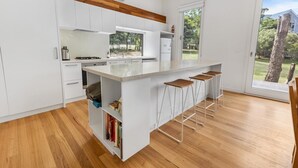 Eine moderne Küche mit weißen Schränken, einer Granitarbeitsplatte und einer eingebauten Kochinsel mit Barhocker.