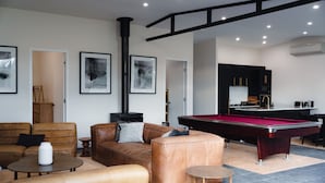A modern living room with a pool table, leather sofas, and a fireplace.