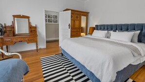 A bedroom with a bed, a dresser, a mirror, and a wardrobe.