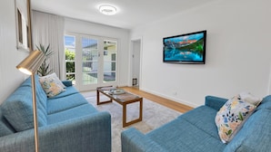 A modern living room with a blue sofa set, a coffee table, and a flat-screen TV on the wall.