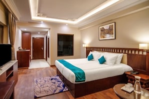 Habitación de hotel con una cama grande, televisión, escritorio y vistas al exterior.