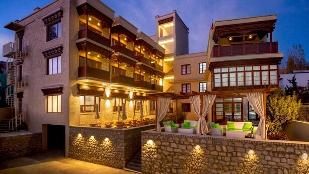 A multi-story hotel with outdoor seating areas, stone walls, and balconies.