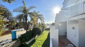 A courtyard with a white building, palm trees, and a clear sky.