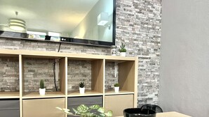 A modern living room with a wooden TV stand, a flat-screen TV, and a stone-patterned wall.