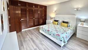 A bedroom with a large bed, wooden wardrobe, bedside tables, and a nightstand.