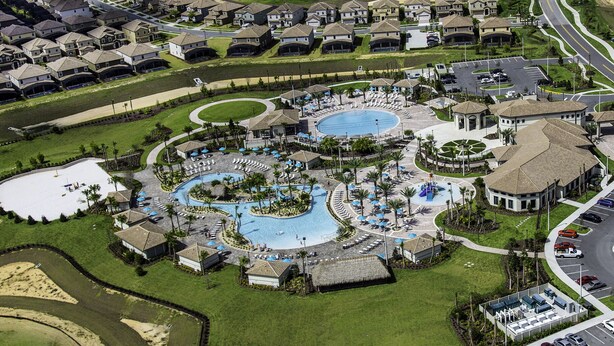 An aerial view of a residential area with multiple swimming pools, a central courtyard, and a parking lot. - 8BR • Arcade & Game Room • 2 Theaters • Pool & Spa (Davenport)