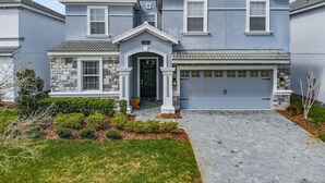 A two-story house with a stone facade, a garage, and a well-maintained front yard. - 8BR • Arcade & Game Room • 2 Theaters • Pool & Spa (Davenport)