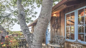 A wooden building with large windows and a porch area with outdoor furniture. - 3879 Lucy's Treehouse ~Unique Vintage Redwood Home (Carmel)