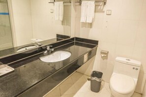 A bathroom with a black countertop sink, a mirror, a toilet, and a trash bin. - Xingtian Hotel (Yueyang)
