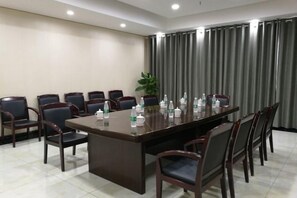 Un salón de conferencias con una larga mesa, sillas y botellas de agua.