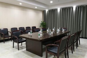 Un salón de conferencias con una larga mesa, sillas y botellas de agua.