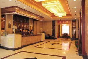Un vestíbulo de hotel con mostrador de recepción, una gran araña y un piso limpio y pulido.