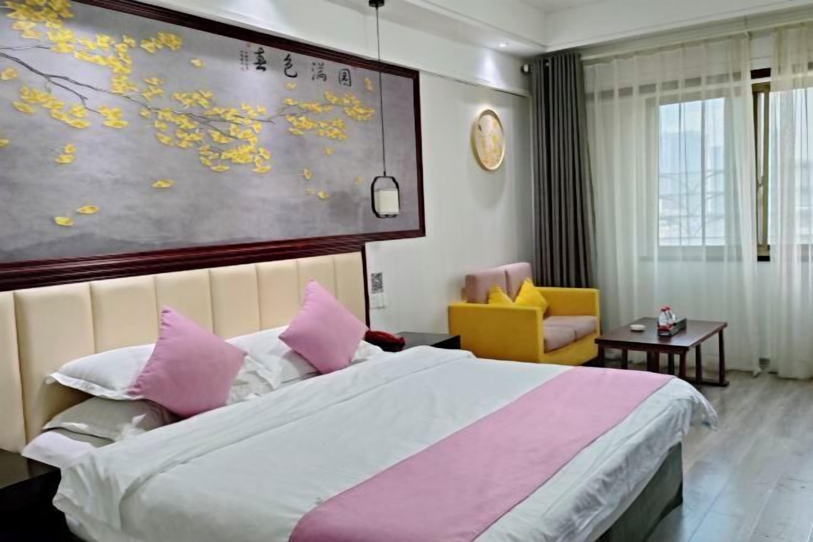 Una habitación de hotel con una cama, un cuadro, una silla, una mesa y una ventana.