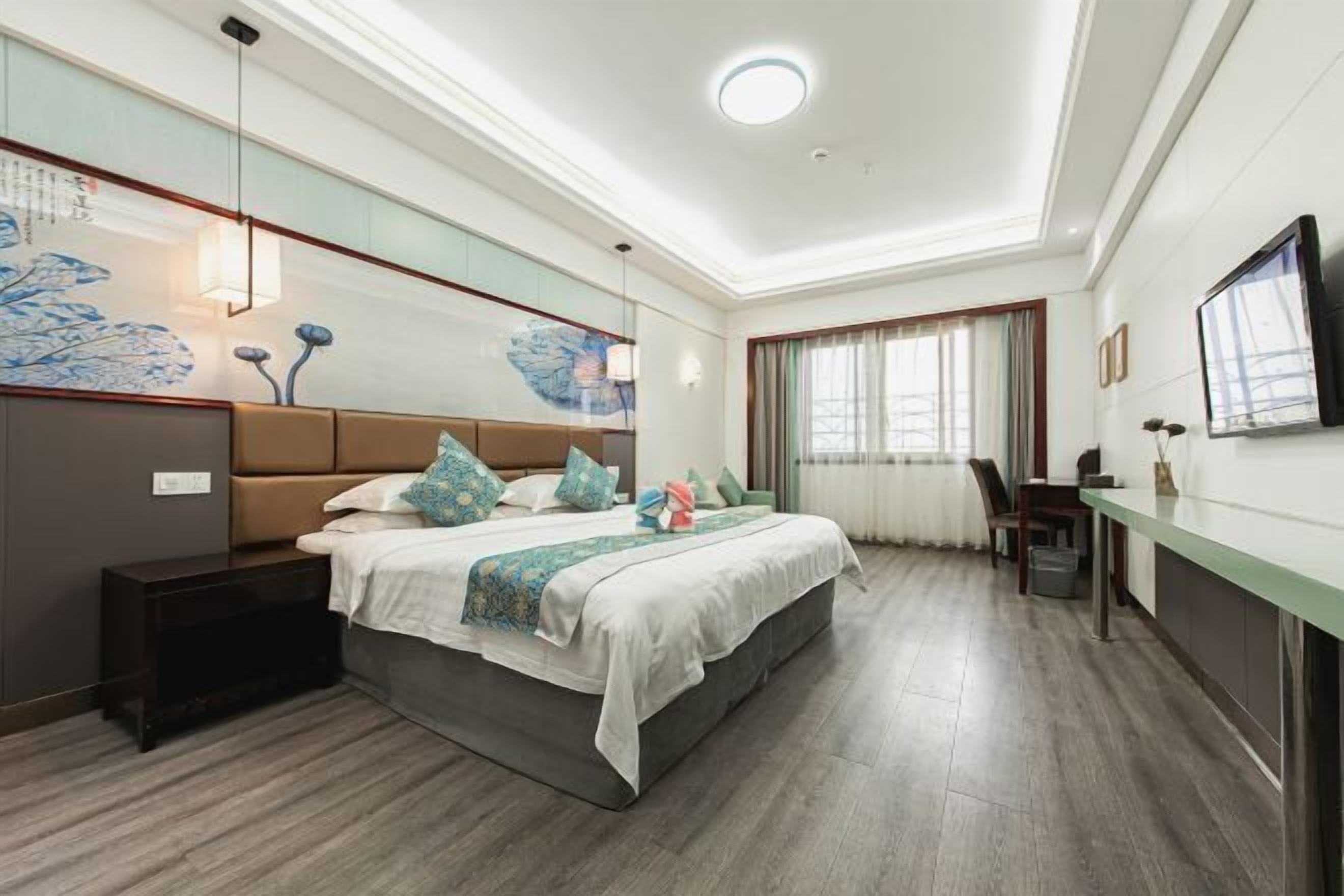 A modern hotel room with a large bed, a desk, and a television.