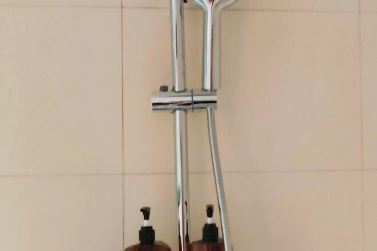 A bathroom with a shower and two soap dispensers on the wall.