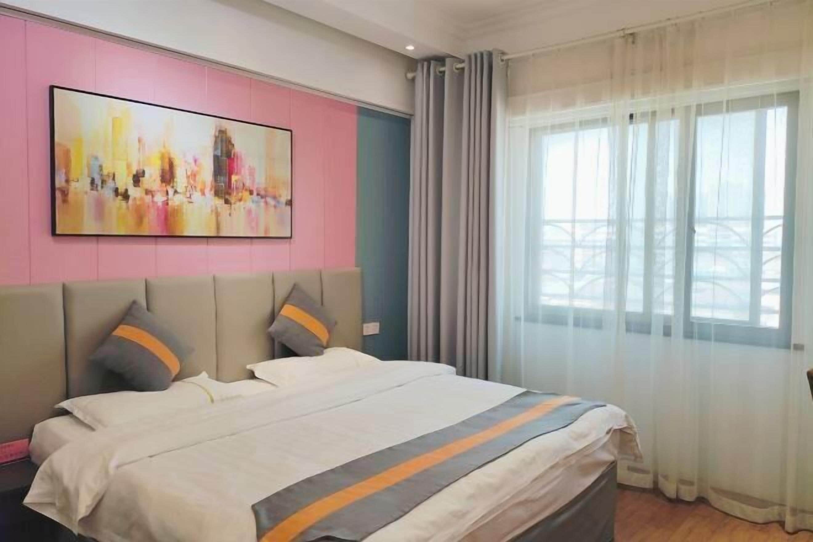 A hotel room with a bed, a large abstract painting on the wall, and a window with curtains.