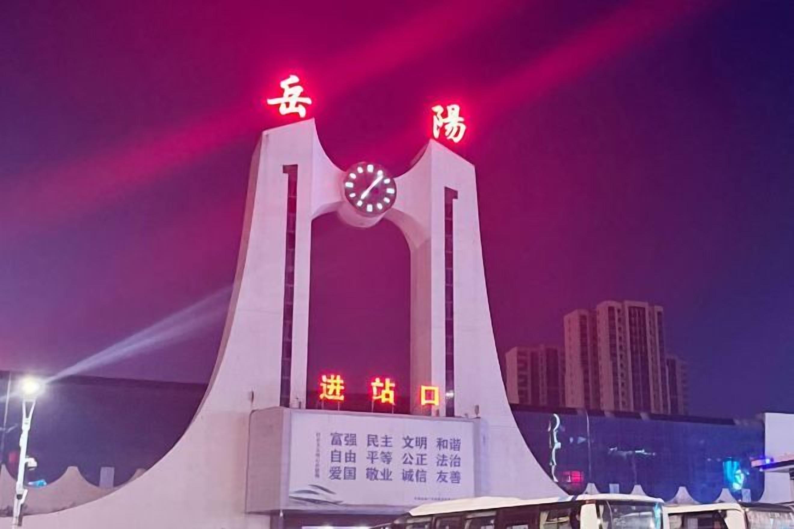 Uma ponte com relógio e caracteres chineses, rodeada por edifícios da cidade.