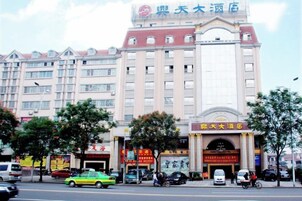 Un hotel de varios pisos con una entrada destacada, numerosas ventanas y un cartel sobre la entrada.