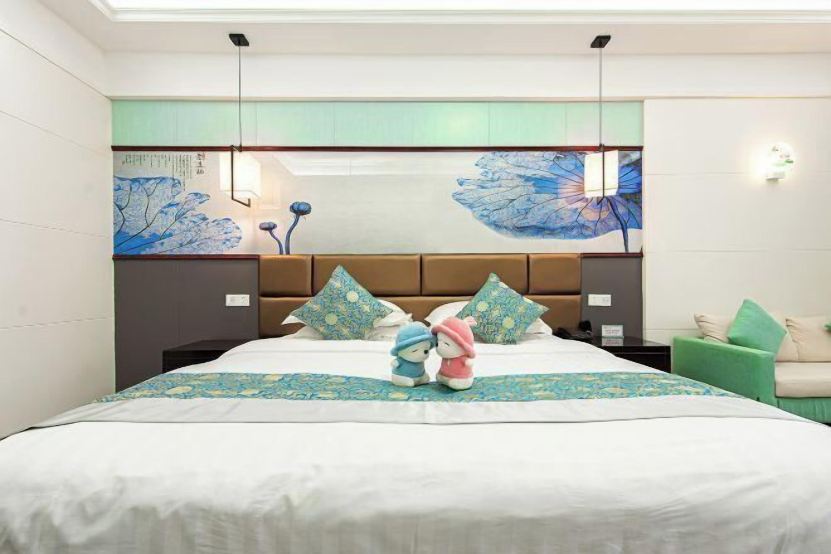 Una habitación de hotel con una cama grande, un cabecero con espejo y un sillón verde.