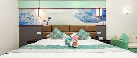 Una habitación de hotel con una cama grande, un cabecero con espejo y un sillón verde.